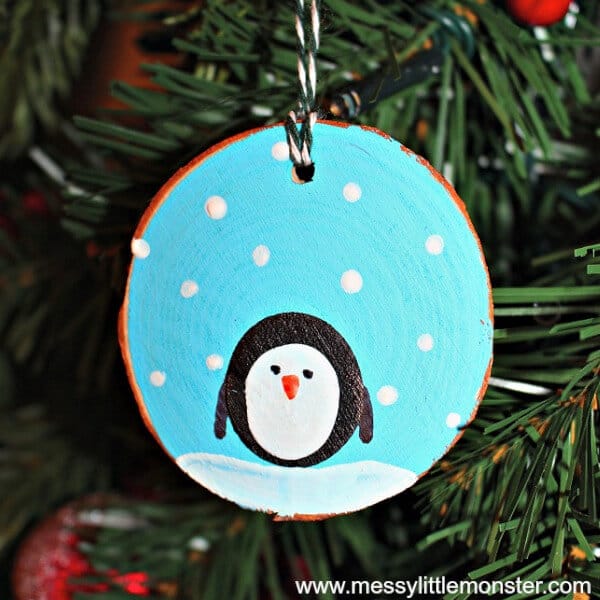 nopin="nopin" Ornament featuring a penguin on a wood slice ornament hanging from a Christmas tree