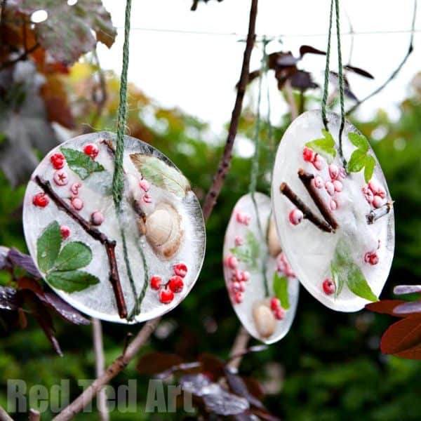 nopin="nopin" ornaments made with ice and nature elements hanging from a tree outdoors