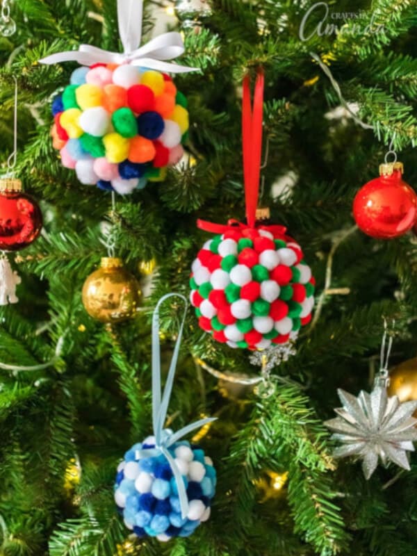 nopin="nopin" Colorful pom pom ornaments hanging from a Christmas tree