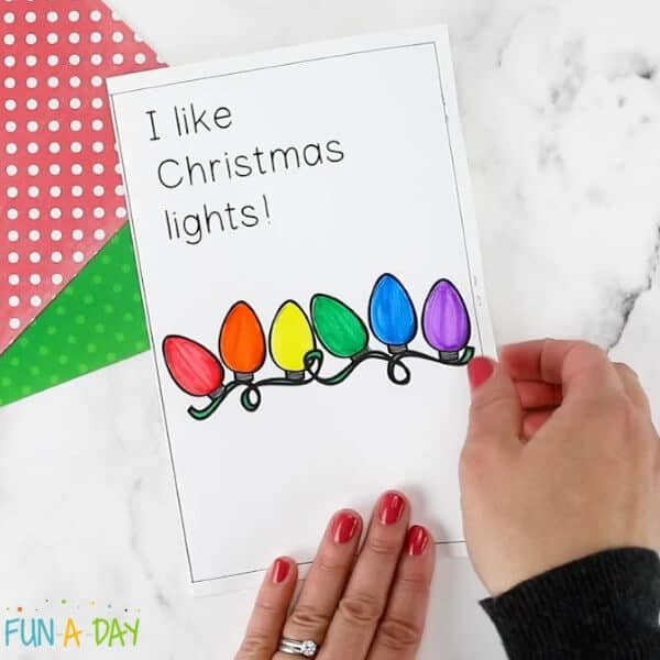 nopin="nopin" hand on a page of a Christmas lights book craft